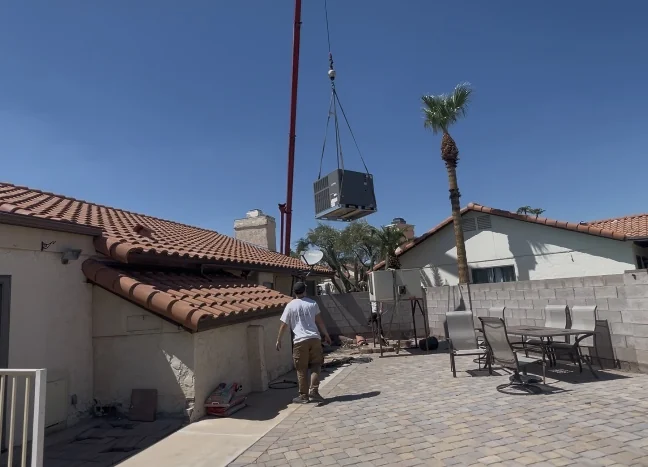 Crane lifting a packaged central HVAC unit onto an Arizona roof