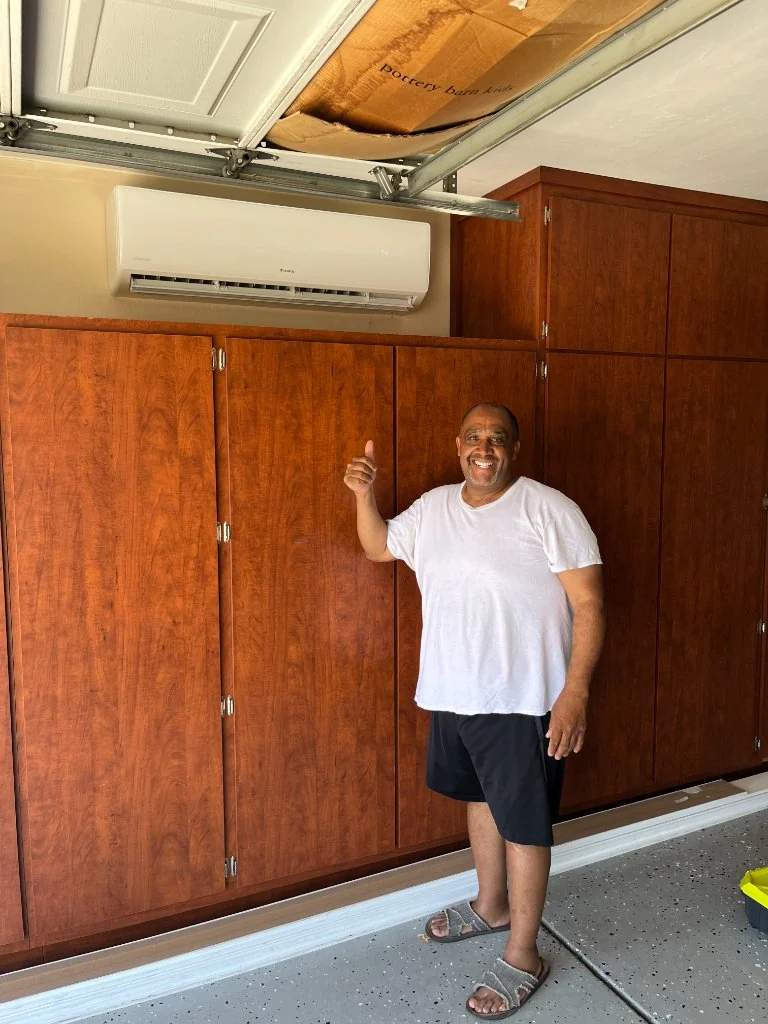 Homeowner giving a thumbs-up beneath a garage mini-split