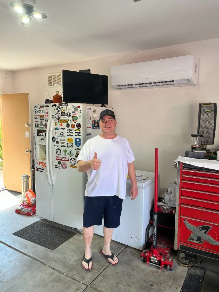 Homeowner giving a thumbs-up beside a garage mini-split