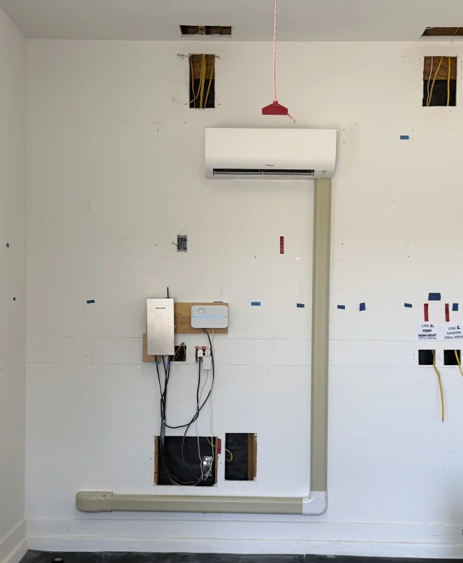Wall-mounted mini-split and covered line routing in a garage during installation