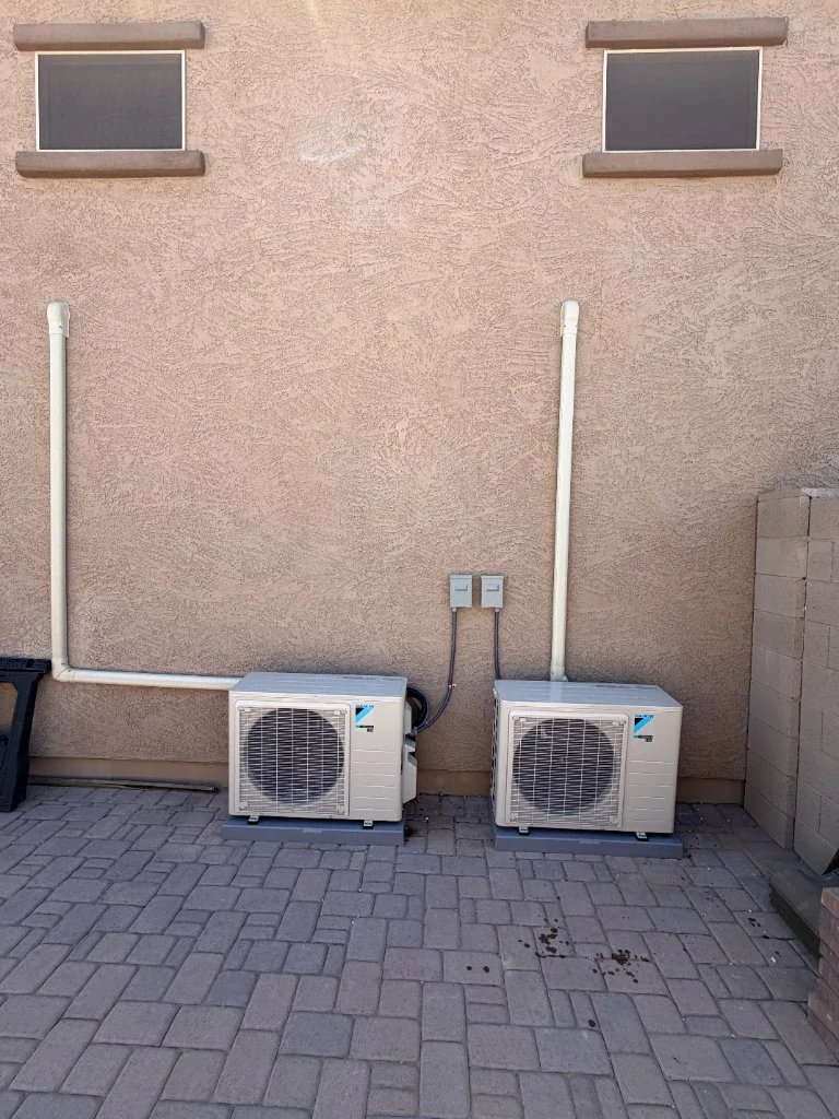 Two outdoor mini-split condensers beside a home